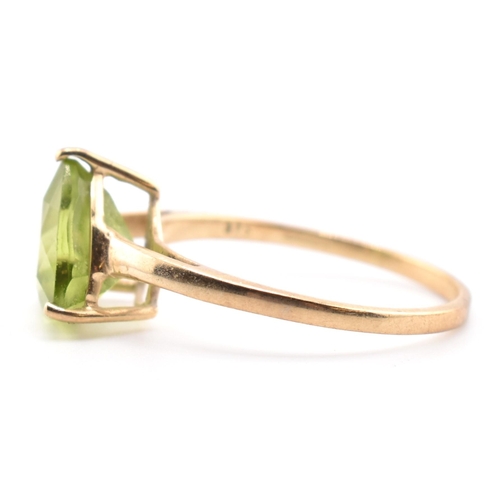 98 - A hallmarked 9ct gold and peridot ring. The ring set with a single trilliant cut peridot to tapering... 