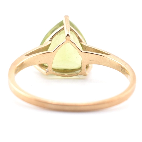 98 - A hallmarked 9ct gold and peridot ring. The ring set with a single trilliant cut peridot to tapering... 