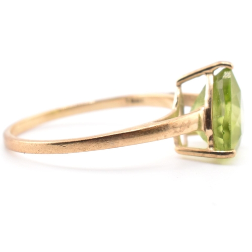 98 - A hallmarked 9ct gold and peridot ring. The ring set with a single trilliant cut peridot to tapering... 