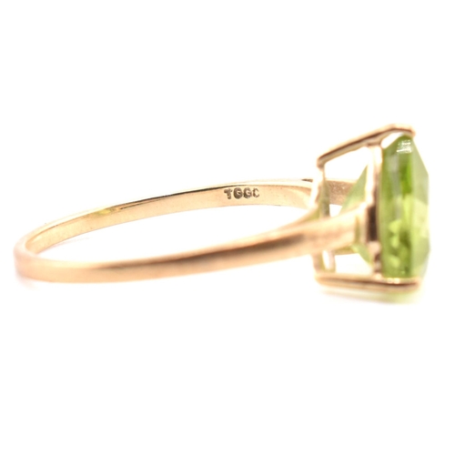 98 - A hallmarked 9ct gold and peridot ring. The ring set with a single trilliant cut peridot to tapering... 