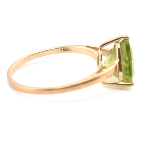 98 - A hallmarked 9ct gold and peridot ring. The ring set with a single trilliant cut peridot to tapering... 