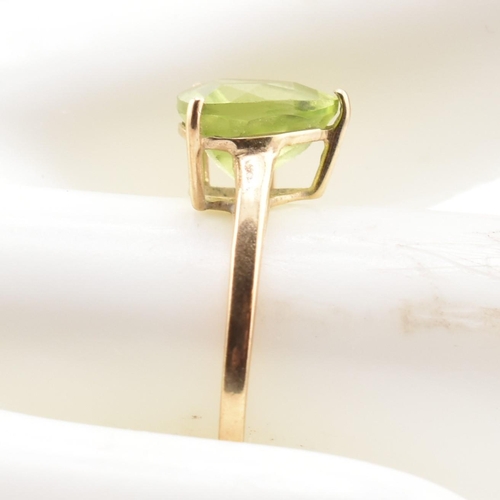 98 - A hallmarked 9ct gold and peridot ring. The ring set with a single trilliant cut peridot to tapering... 