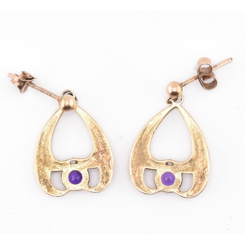 52 - A pair of hallmarked 9ct gold and purple stone pendant earrings. The 9ct yellow gold pendant earring... 