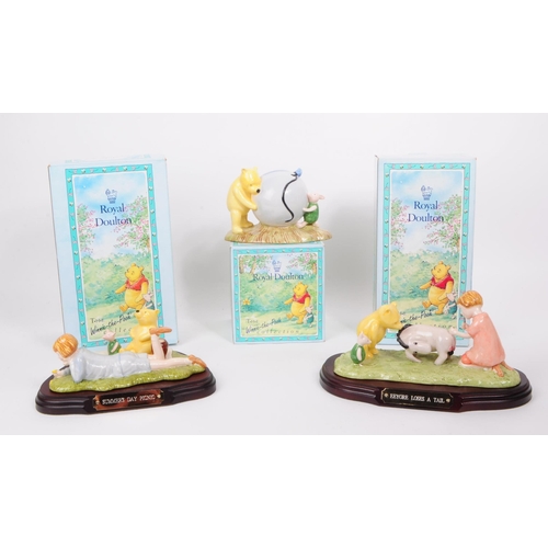 153 - Royal Doulton - Three late 20th century bone china Winnie The Pooh figures. Comprised of Pooh's Blue... 