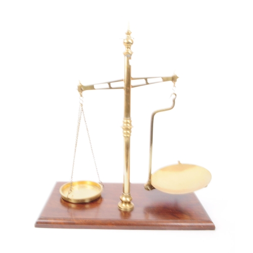 202 - A set of mid 20th century brass weighing scales. The scales raised on a bevelled edge oak wood plint... 