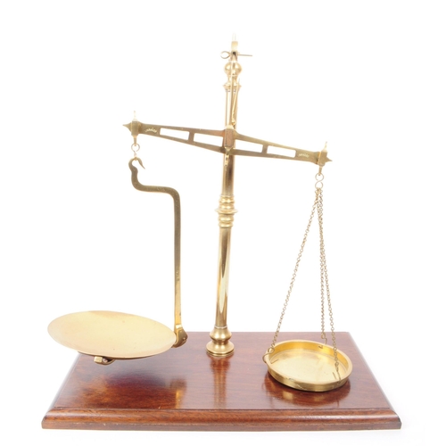 202 - A set of mid 20th century brass weighing scales. The scales raised on a bevelled edge oak wood plint... 