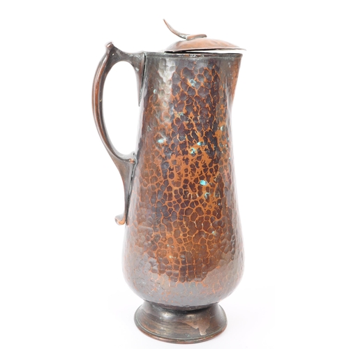 382 - An early 20th century Arts & Crafts hand hammered copper ewer jug. The jug having hinged lid ato... 