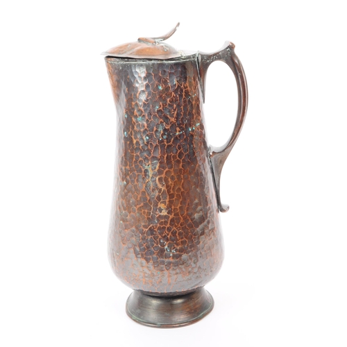 382 - An early 20th century Arts & Crafts hand hammered copper ewer jug. The jug having hinged lid ato... 