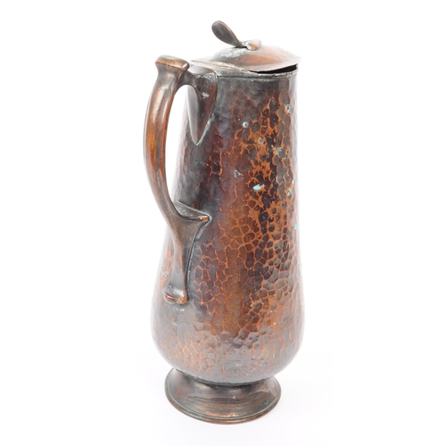 382 - An early 20th century Arts & Crafts hand hammered copper ewer jug. The jug having hinged lid ato... 