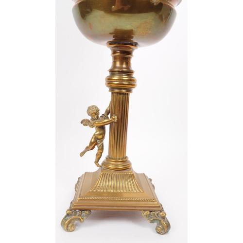 391 - Early 20th century brass columnar oil lamp mounted on four scrolled feat with a brass cherub figure ... 