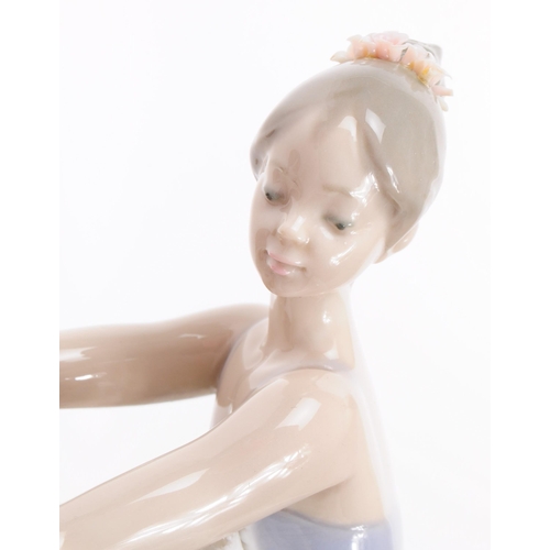 83 - Lladro - Late 20th century porcelain lady Ballerina figure in a stretching pose. Dressed in a lace s... 