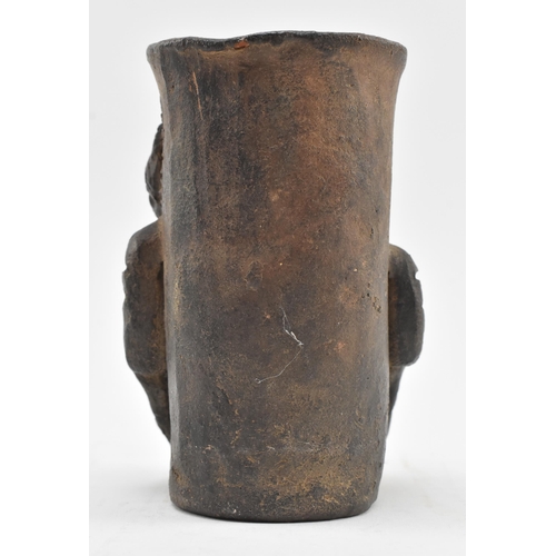 149 - A Central / South American hand moulded terracotta clay black drinking vessel. The vessel cup depict... 