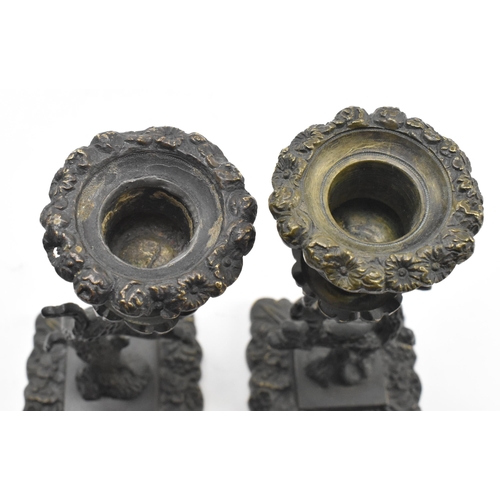 82 - A pair of early 19th century cast iron ornate table candlesticks. The candle holders having a floral... 