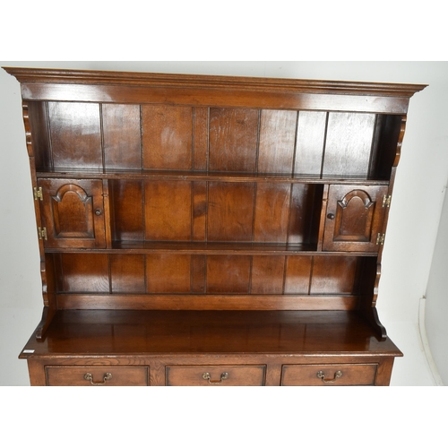 309 - A George III Revival Ipswich solid oak Welsh dresser. The dresser having a flared pediment top with ... 