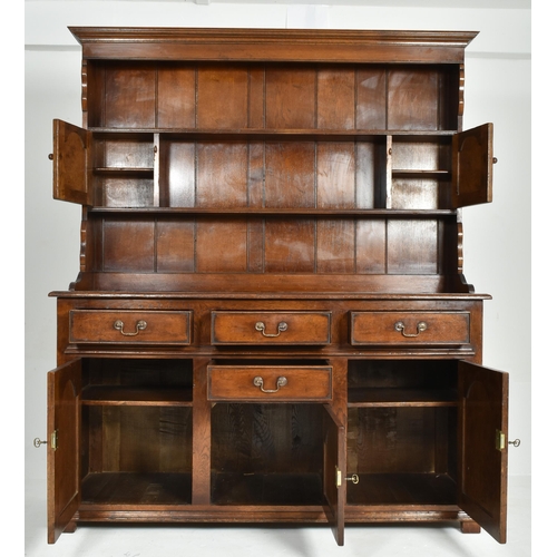 309 - A George III Revival Ipswich solid oak Welsh dresser. The dresser having a flared pediment top with ... 