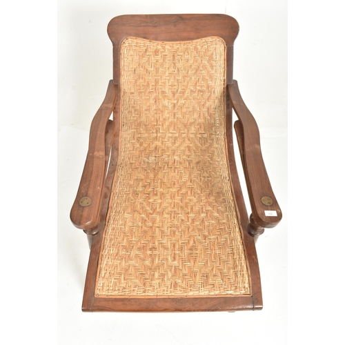 352 - An early 20th century plantation teak & wicker rattan seat lounge chair. The chair having a recl... 