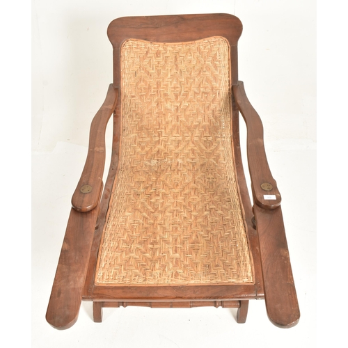 352 - An early 20th century plantation teak & wicker rattan seat lounge chair. The chair having a recl... 