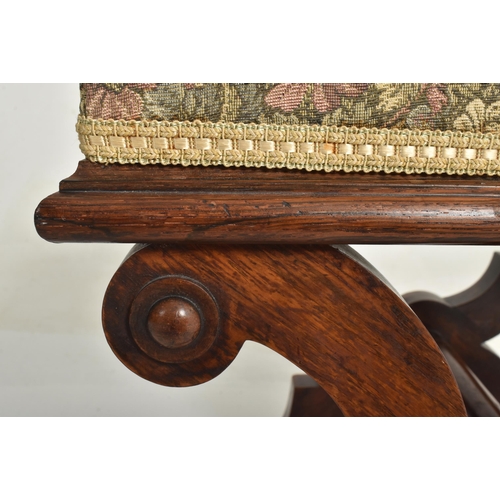 452 - A late 19th century mahogany & upholstered X-framed stool / piano seat. The stool having a padde... 