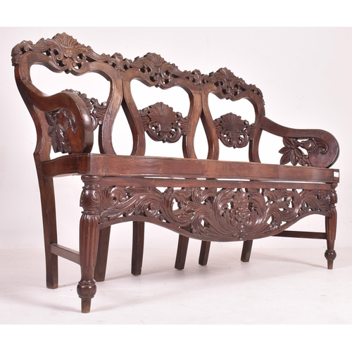 545 - An Indo - Portuguese manner hardwood and cane hall bench. The bench having a carved pierced back res... 