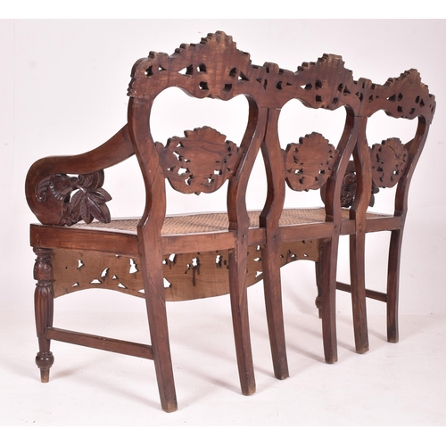 545 - An Indo - Portuguese manner hardwood and cane hall bench. The bench having a carved pierced back res... 