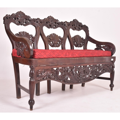 547 - An Indo - Portuguese manner hardwood hall bench settle. The bench having a carved pierced back rest ... 