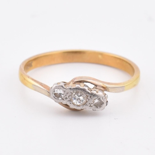 113 - An 18ct gold and diamond three stone crossover ring. Marked 18ct to inner shank. Weighs 3.1g. Size S... 