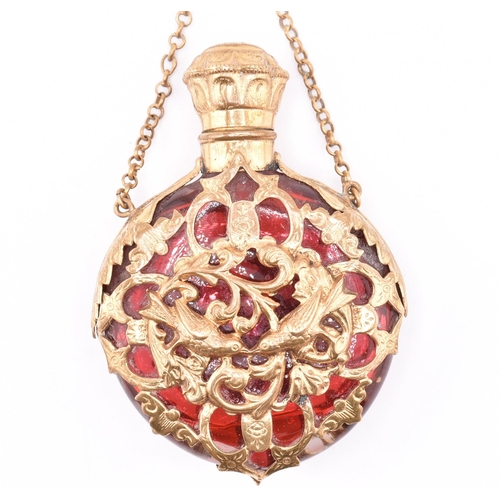 12 - A gilt and cranberry glass scent bottle. The cranberry glass scent bottle having a pierced gilt meta... 