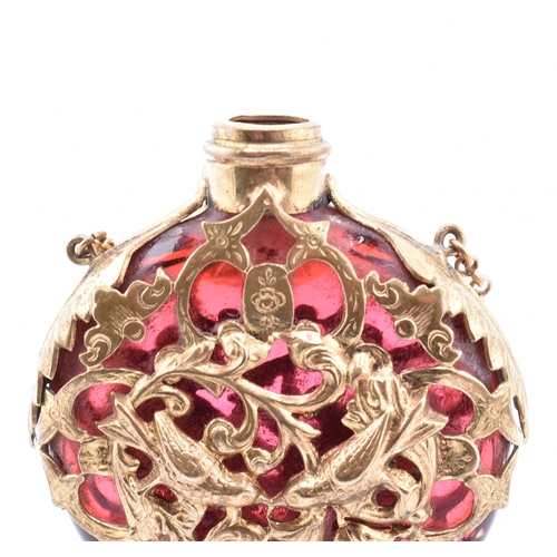 12 - A gilt and cranberry glass scent bottle. The cranberry glass scent bottle having a pierced gilt meta... 