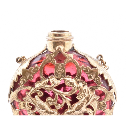 12 - A gilt and cranberry glass scent bottle. The cranberry glass scent bottle having a pierced gilt meta... 