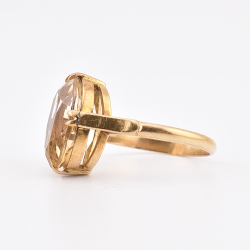 129 - An 18ct gold and citrine ring. The ring set with a single double claw set oval cut citrine to polish... 