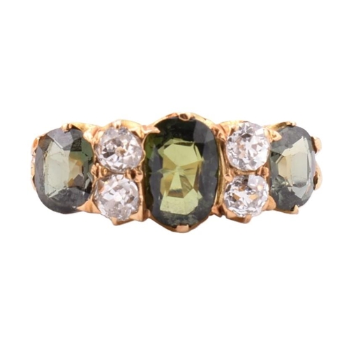 15 - A gold green sapphire and diamond three stone ring. The ring set with a central oval cut green sapph... 