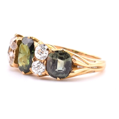 15 - A gold green sapphire and diamond three stone ring. The ring set with a central oval cut green sapph... 