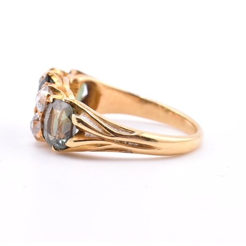 15 - A gold green sapphire and diamond three stone ring. The ring set with a central oval cut green sapph... 