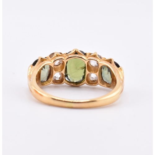 15 - A gold green sapphire and diamond three stone ring. The ring set with a central oval cut green sapph... 