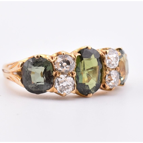 15 - A gold green sapphire and diamond three stone ring. The ring set with a central oval cut green sapph... 