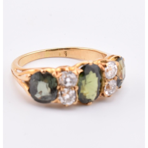 15 - A gold green sapphire and diamond three stone ring. The ring set with a central oval cut green sapph... 