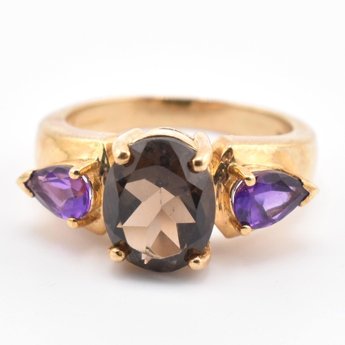 336 - A hallmarked 9ct gold smoky quartz and amethyst three stone ring. The ring set with a central four c... 