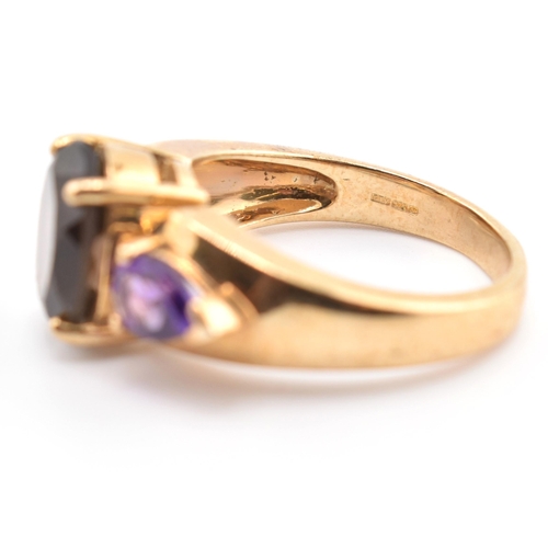 336 - A hallmarked 9ct gold smoky quartz and amethyst three stone ring. The ring set with a central four c... 