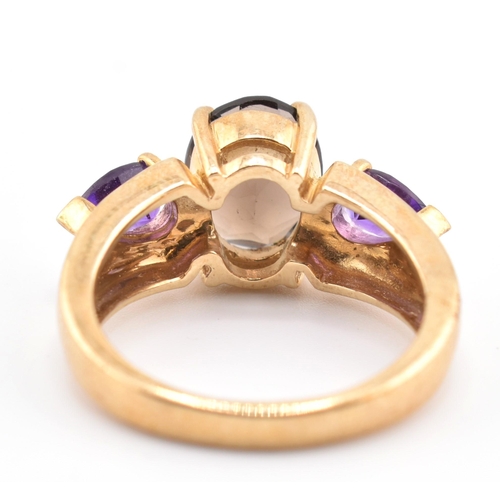 336 - A hallmarked 9ct gold smoky quartz and amethyst three stone ring. The ring set with a central four c... 