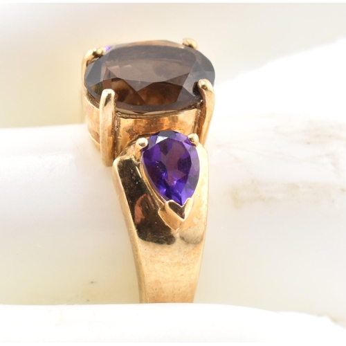 336 - A hallmarked 9ct gold smoky quartz and amethyst three stone ring. The ring set with a central four c... 