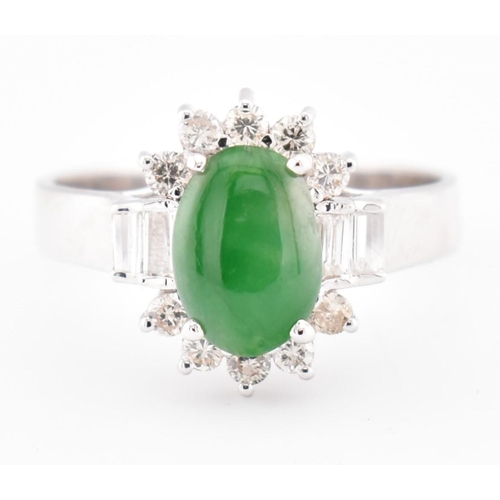 378 - An 18ct white gold jade and diamond halo ring. The 18ct white gold ring set with a central oval jade... 