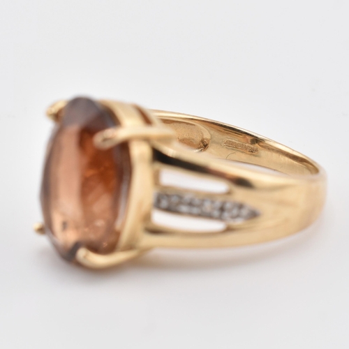 386 - A hallmarked 9ct gold imperial topaz and white topaz ring. The 9ct yellow gold ring set with a centr... 