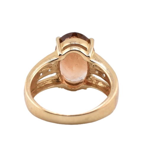 386 - A hallmarked 9ct gold imperial topaz and white topaz ring. The 9ct yellow gold ring set with a centr... 