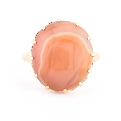 408 - A gold and agate ring. The ring having a claw set round agate cabochon to tapered shoulders and poli... 