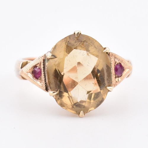 409 - An 18ct gold citrine and ruby ring. The 18ct yellow gold ring having a central six claw set oval cut... 