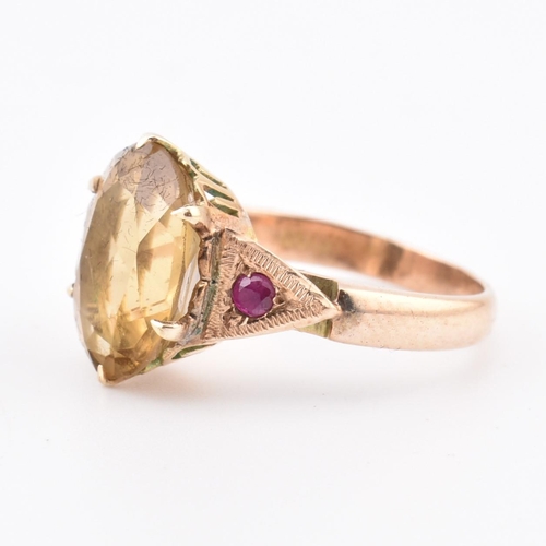 409 - An 18ct gold citrine and ruby ring. The 18ct yellow gold ring having a central six claw set oval cut... 