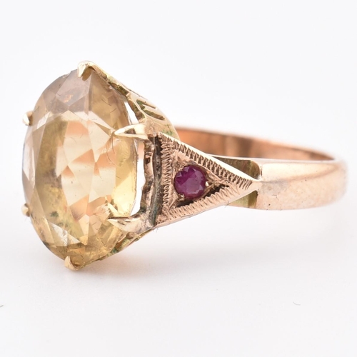 409 - An 18ct gold citrine and ruby ring. The 18ct yellow gold ring having a central six claw set oval cut... 