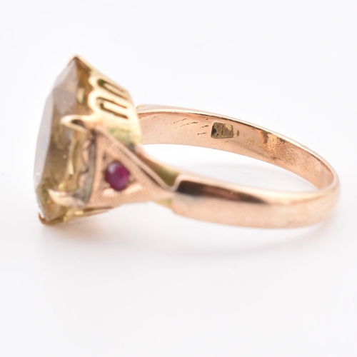 409 - An 18ct gold citrine and ruby ring. The 18ct yellow gold ring having a central six claw set oval cut... 