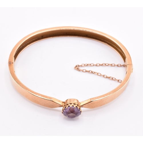 5 - A 15ct gold and amethyst bangle. The 15ct gold bangle set with a single claw mounted round cut ameth... 