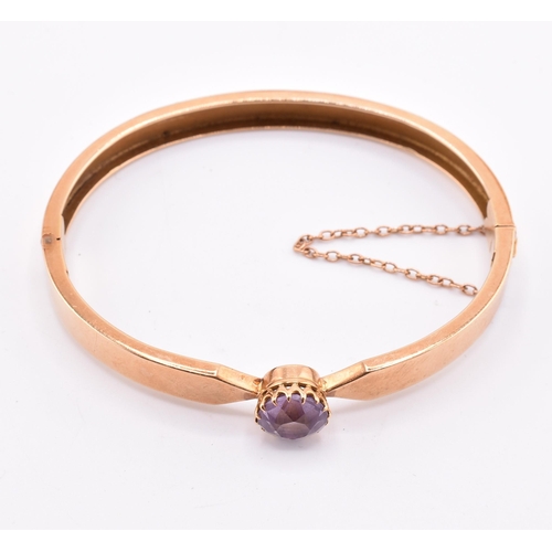 5 - A 15ct gold and amethyst bangle. The 15ct gold bangle set with a single claw mounted round cut ameth... 